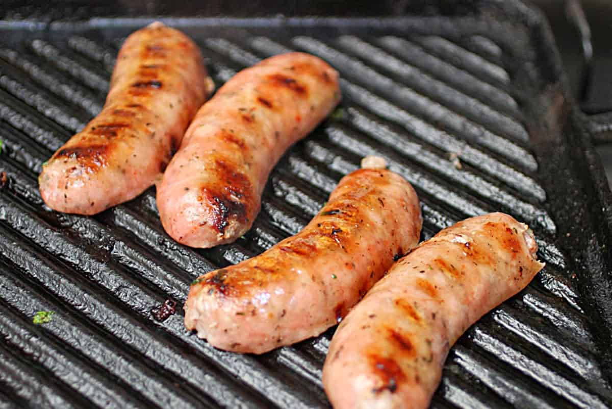 Butterflied chorizos being grilled on a cast iron ridged skillet.
