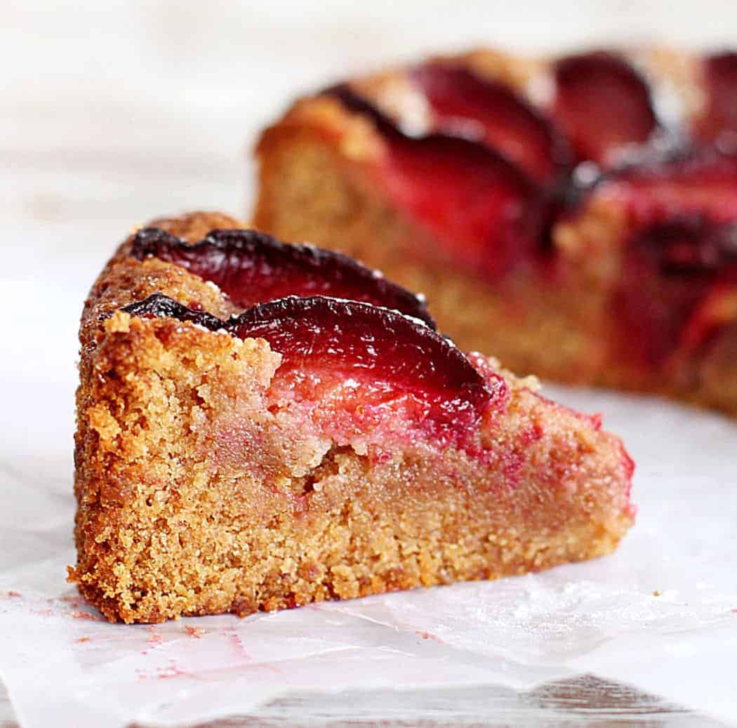 Close-up of almond plum cake on white parchment paper.