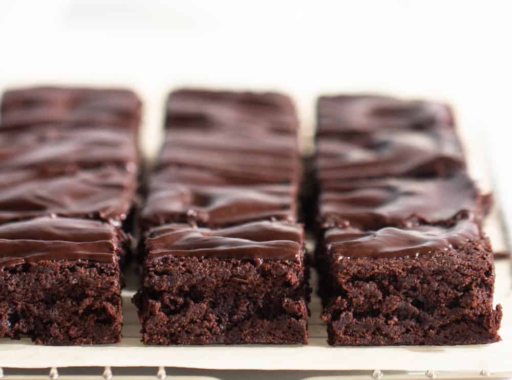Squares of cocoa brownies with ganache, white surface