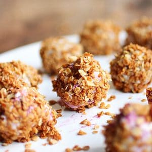 Several granola ice cream truffles on a white plate.