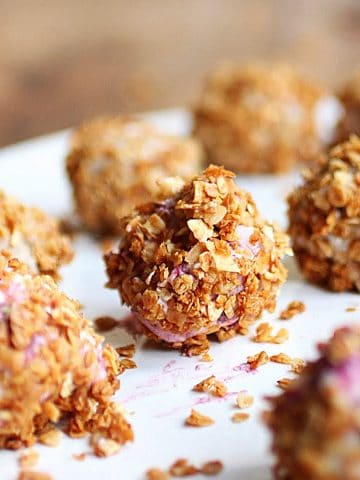 Several granola ice cream truffles on a white plate.