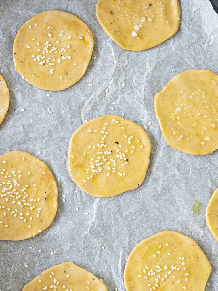 Sea salt sprinkled round crackers on white parchment paper.