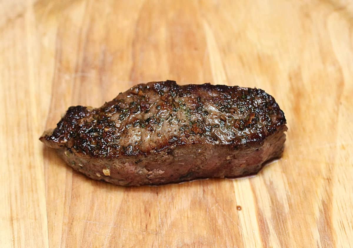Seared piece of rump steak resting on wooden plate