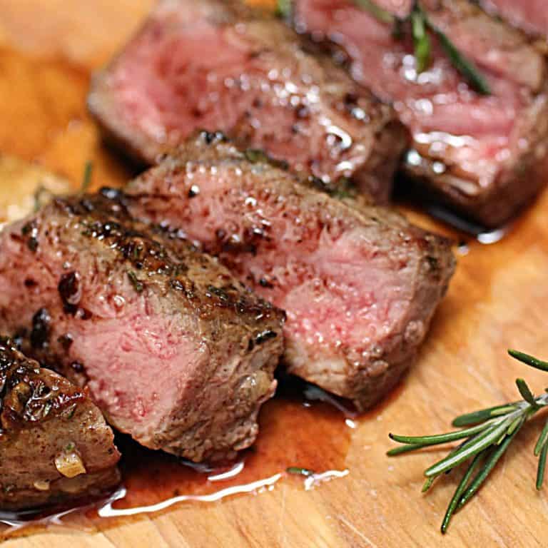 Very close up view of juicy slices of rosemary steak on a wood board
