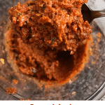 Spoon with sun dried tomato pesto over glass jar