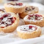 Several mini jam cakes on white cloth, sprinkled with powdered sugar
