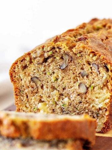 Cut loaf of zucchini bread with slices, white background