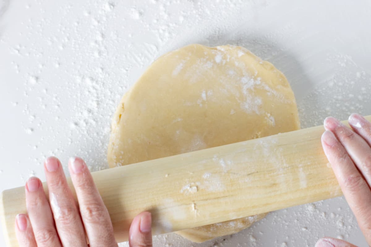 Rolling sweet pie crust on white surface.