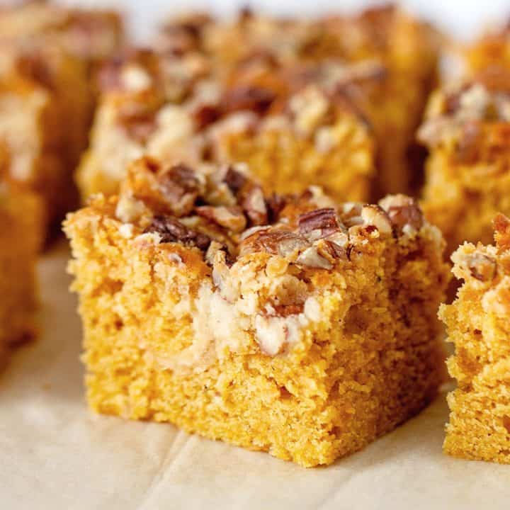 Beige parchment paper with pumpkin pecan cake squares.