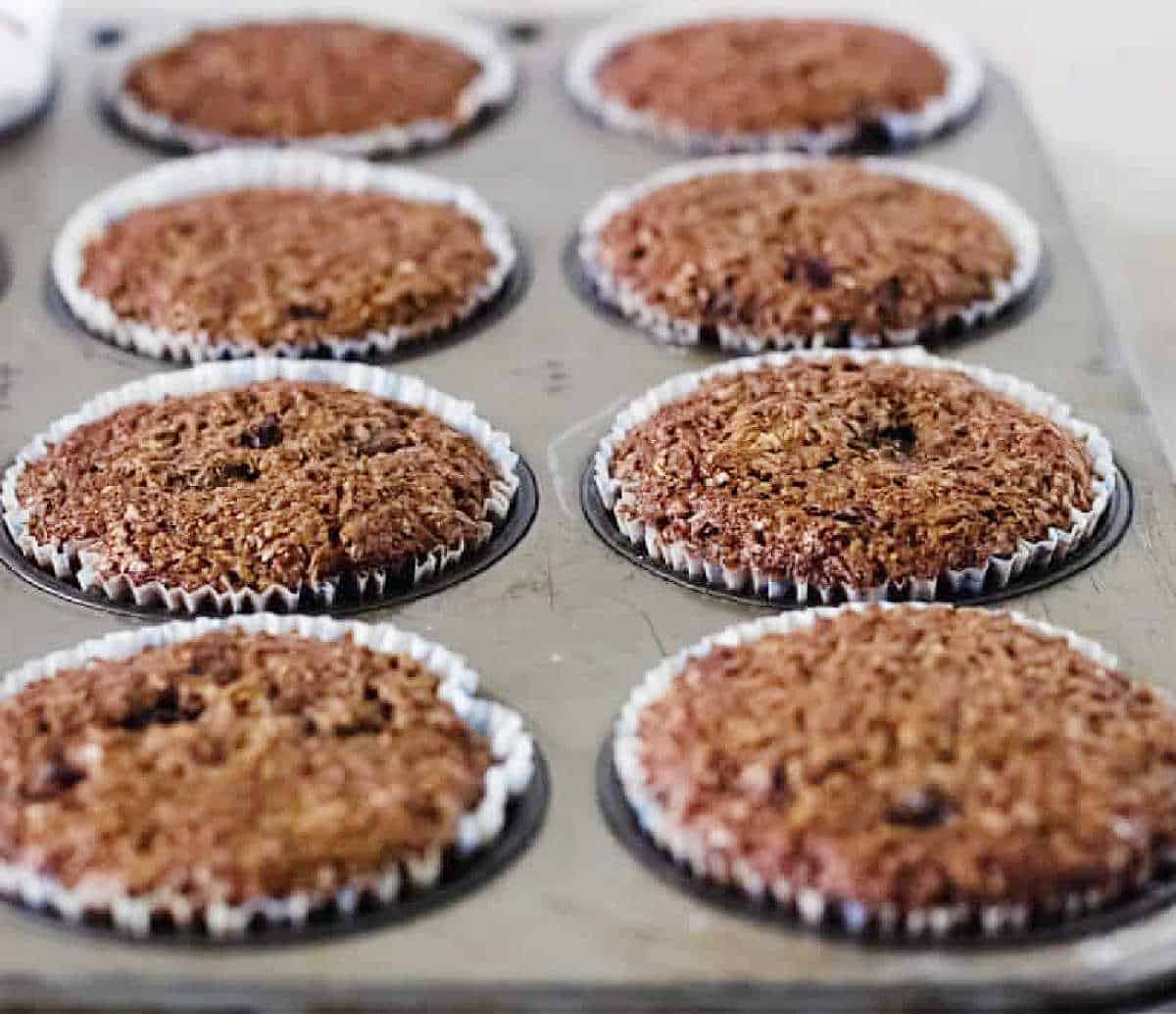 Baked bran muffins with paper liners in a metal muffin pan.