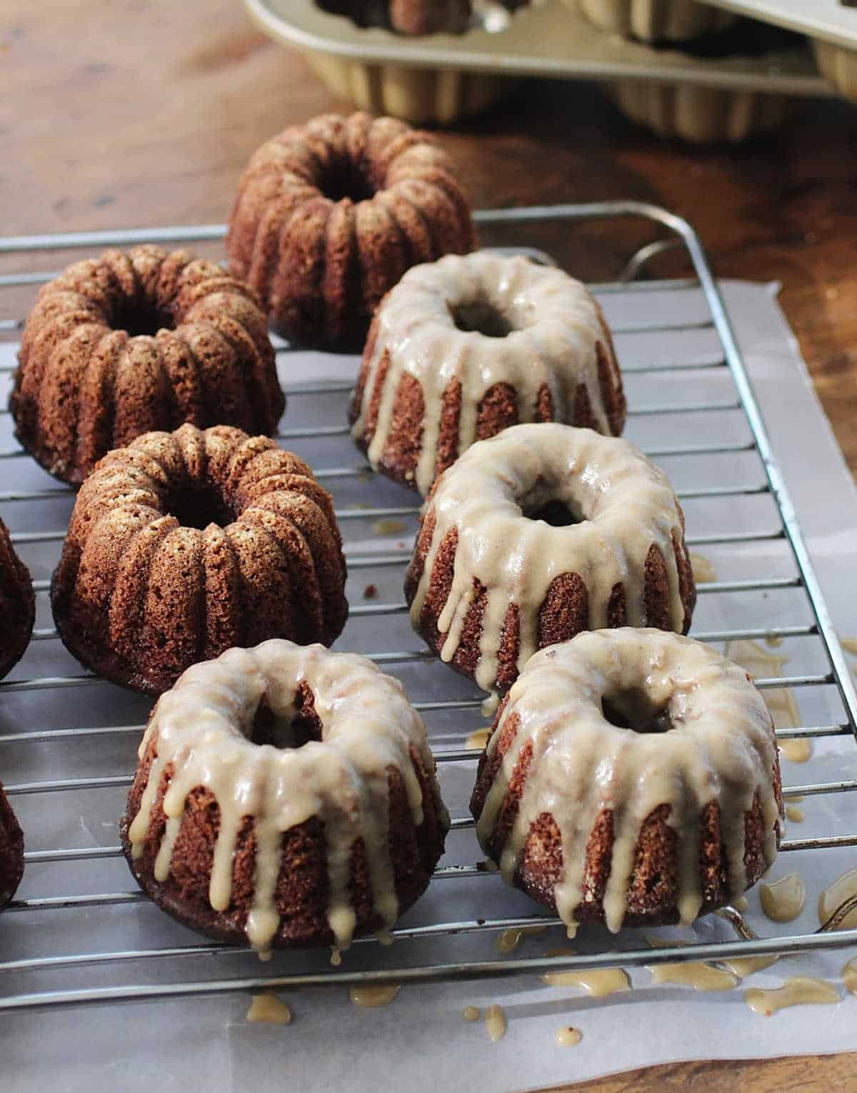 Top view of glazed and plain chocolate mini bundt cakes on a cooling rack with parchment paper below.