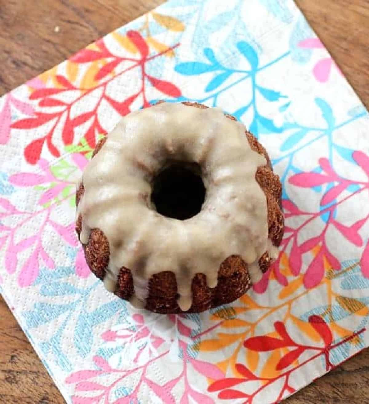 Colorful napkin on a wooden surface with a glazed chocolate mini bundt cake.