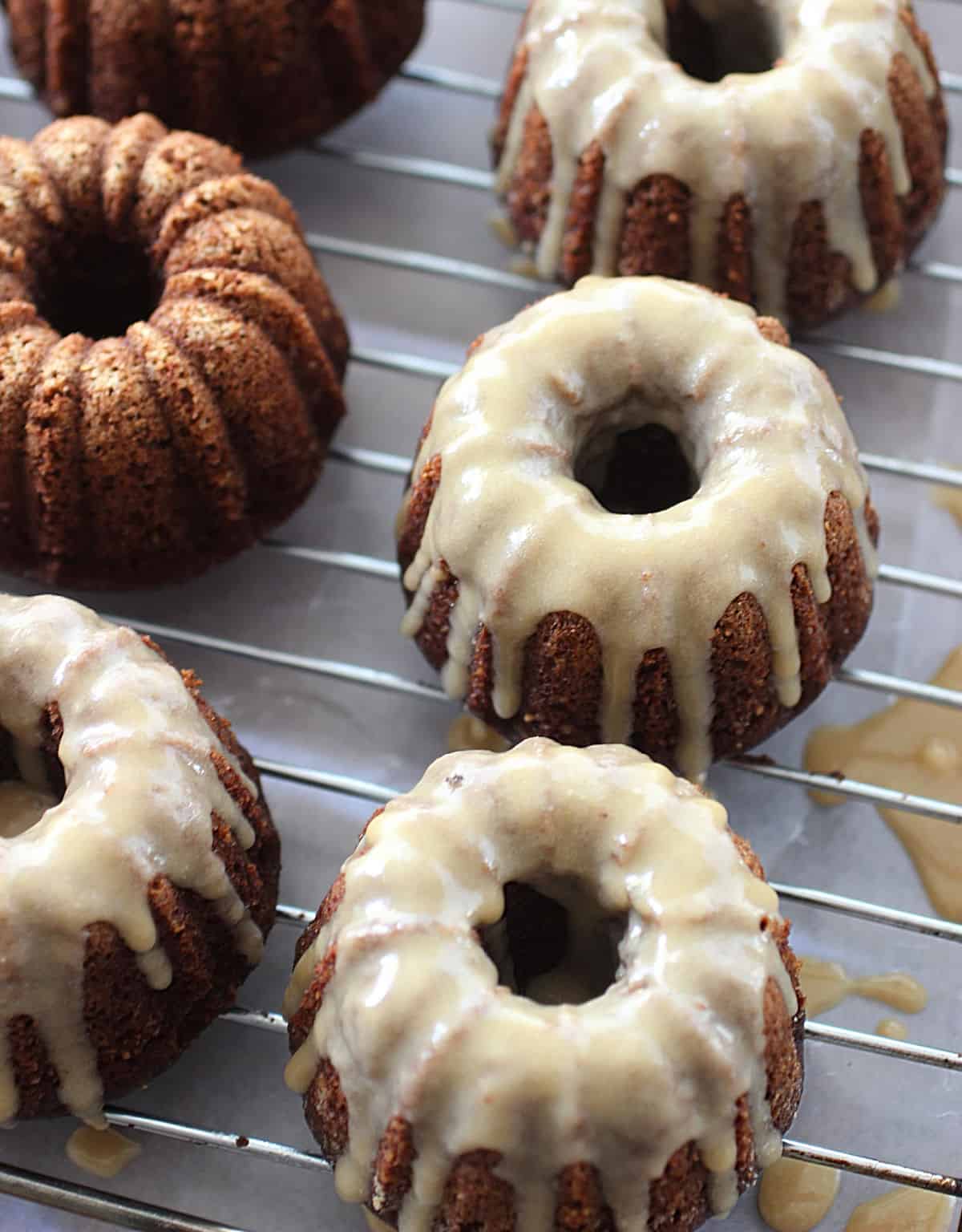 Close of glazed mini bundt cake on a wire rack with parchment paper, seen from above.