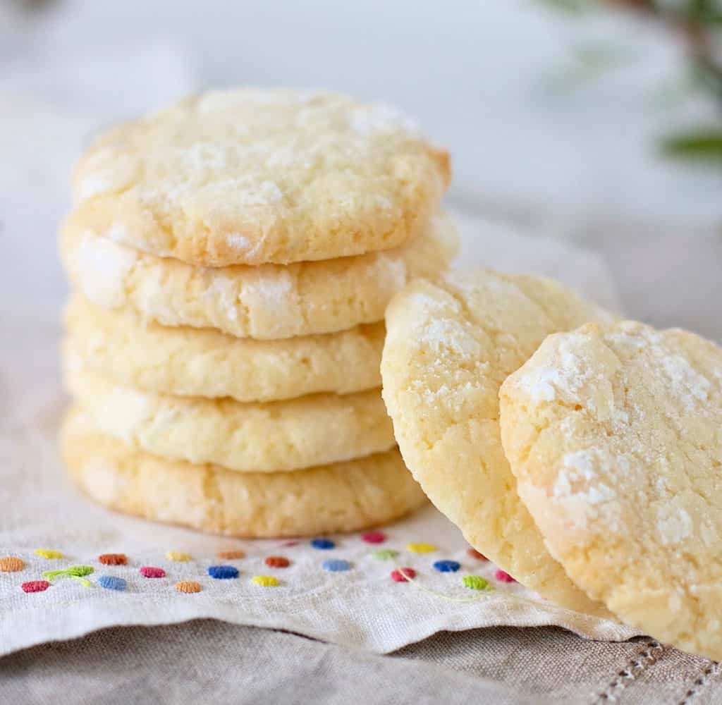 Stack of lemon crinkle cookies, white cloth with color dots