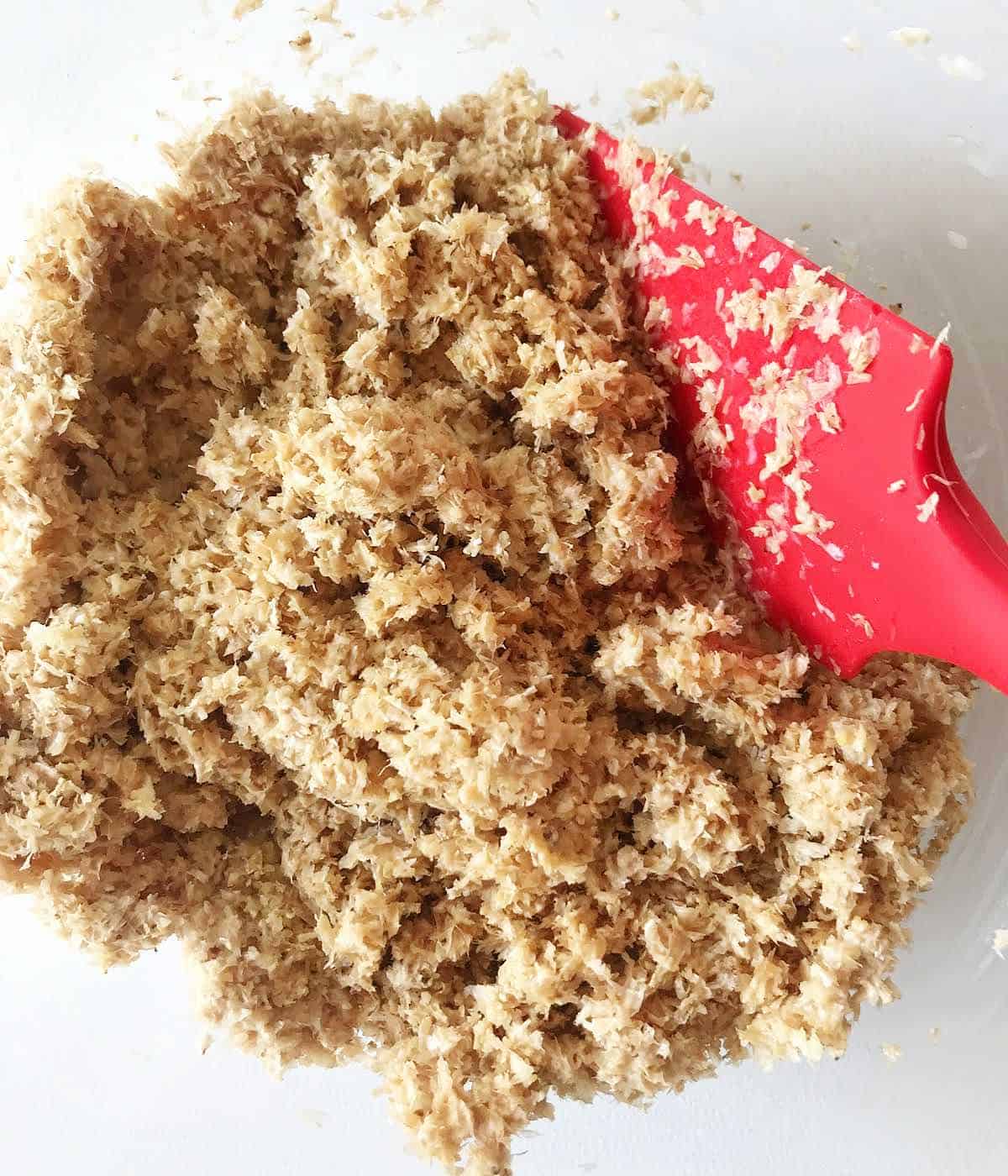 Mixing bran with liquid for muffins in a bowl with a red spatula. 