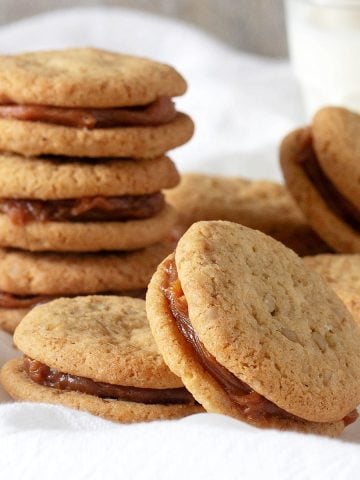 Several walnut alfajores with dulce de leche on a white linen.