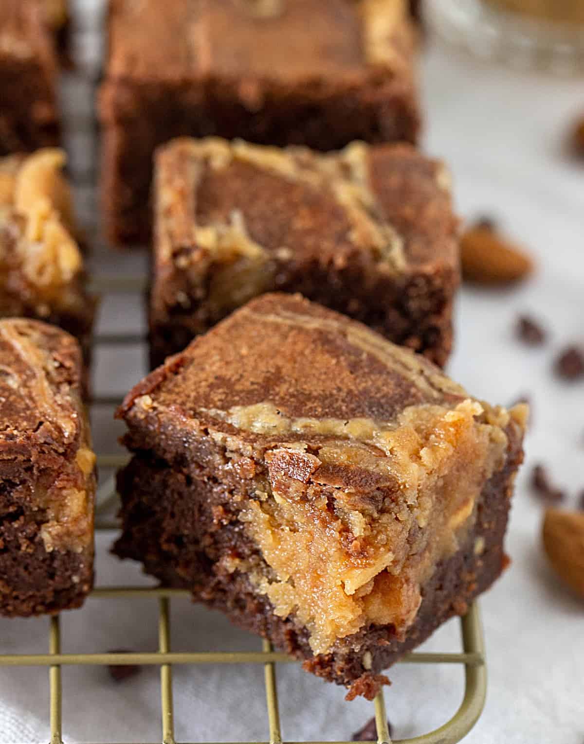 Marbled brownie squares on a golden wire rack.