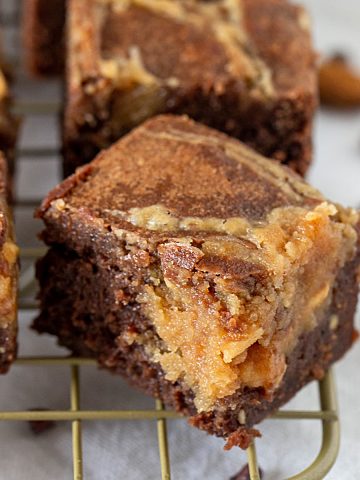 Close-up of peanut butter brownie square on gold wire rack, white surface