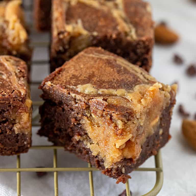 Close-up of peanut butter brownie square on gold wire rack, white surface