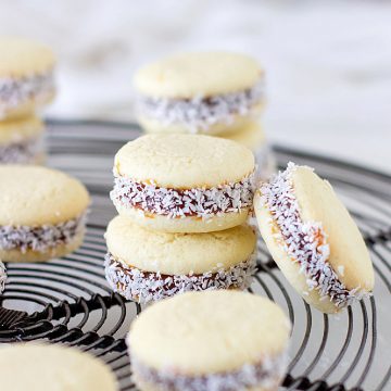 Several stacked alfajores on a grey wire rack.