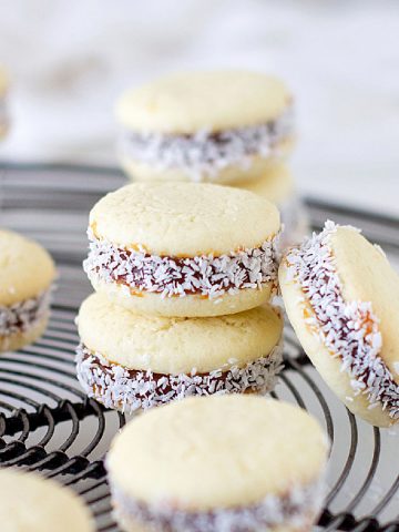 Several stacked alfajores on a grey wire rack.