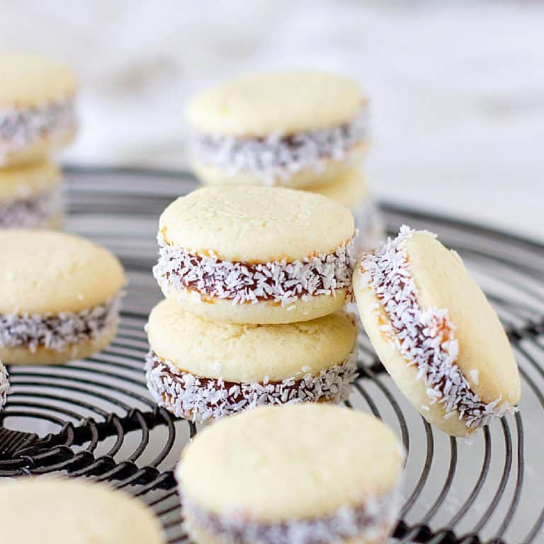 Several stacked alfajores on grey wire rack.