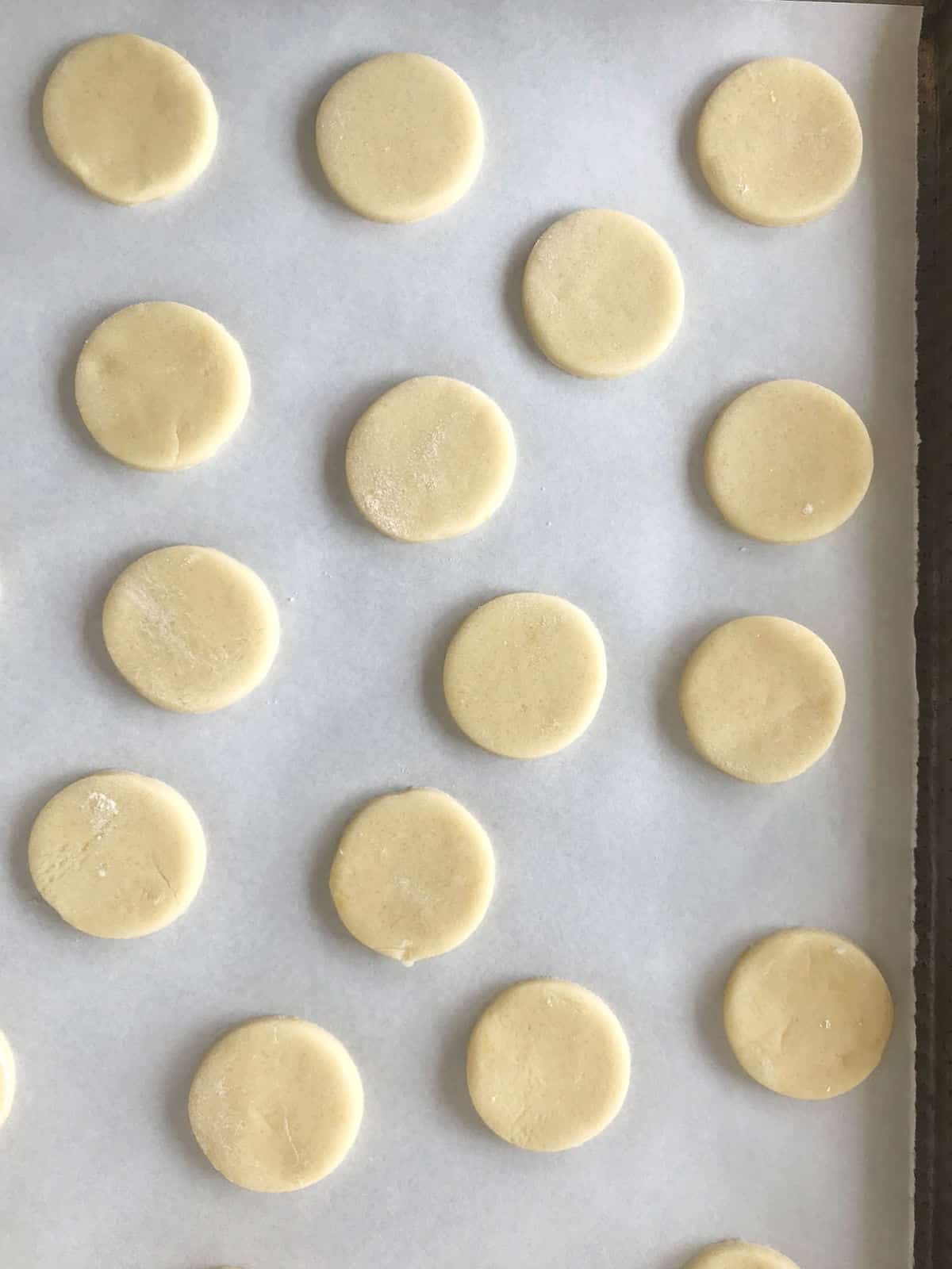 Unbaked cornstarch cookie rounds on white parchment paper.
