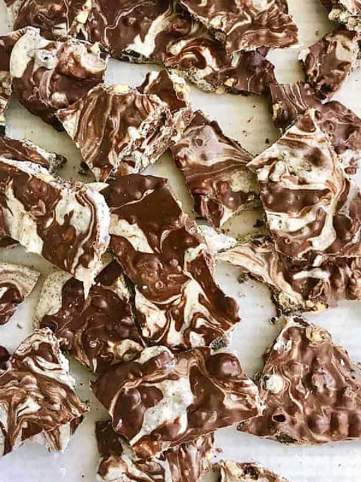 Pieces of marbled white and brown chocolate bark on a white surface. Top view.