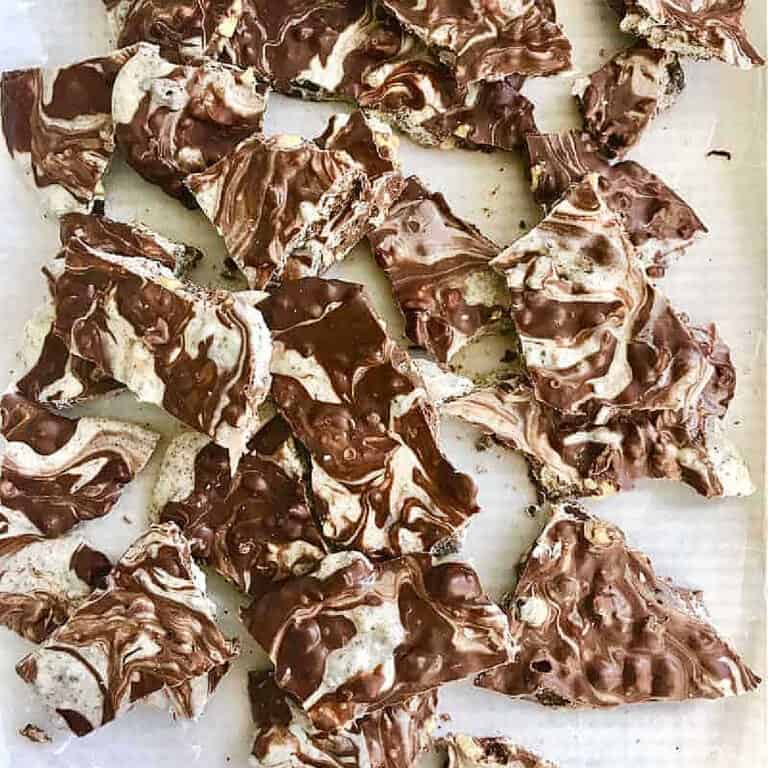 Pieces of marbled white and brown chocolate bark on a white surface. Top view.