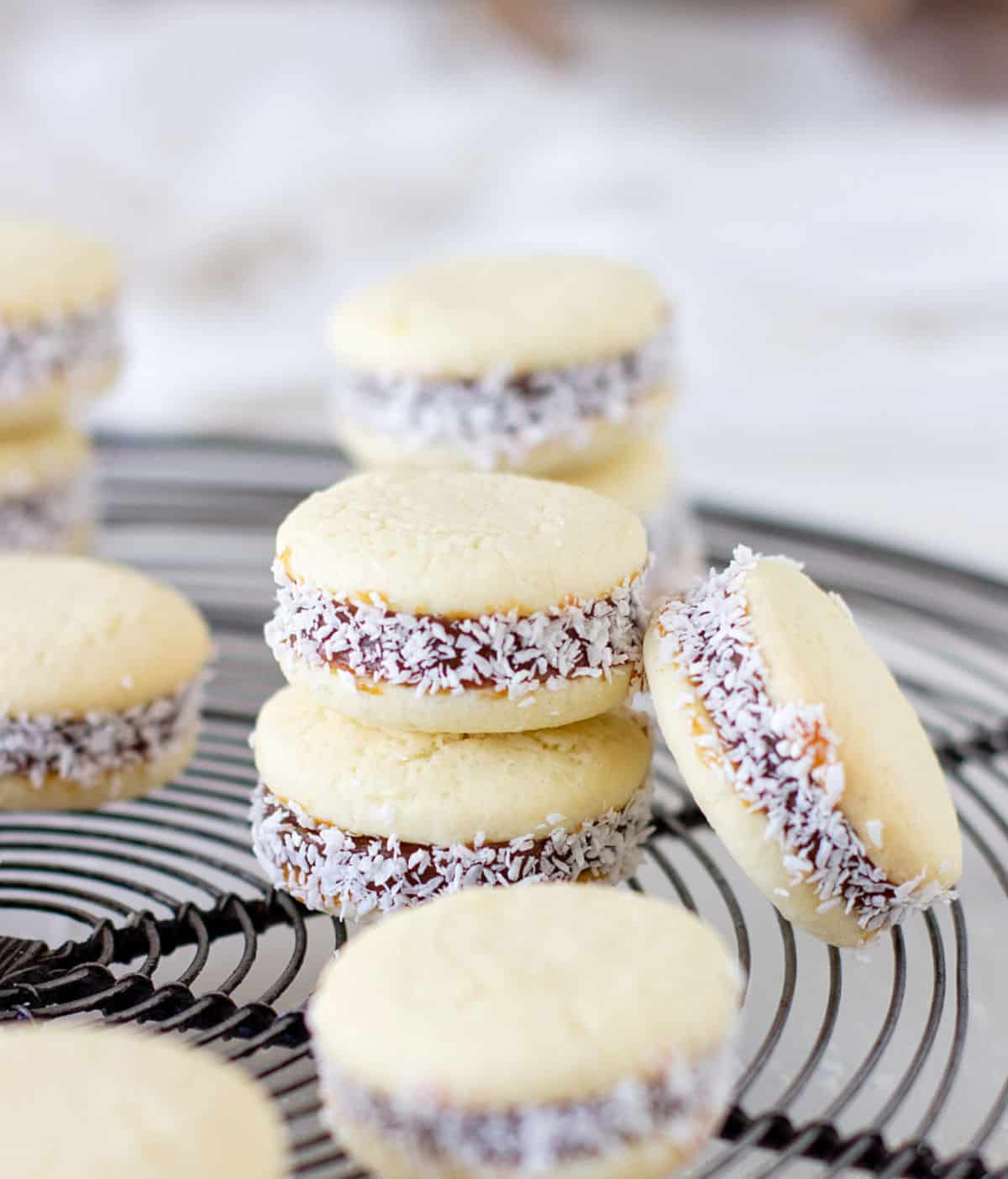 Metal wire rack with several cornstarch alfajores with coconut. White background. 