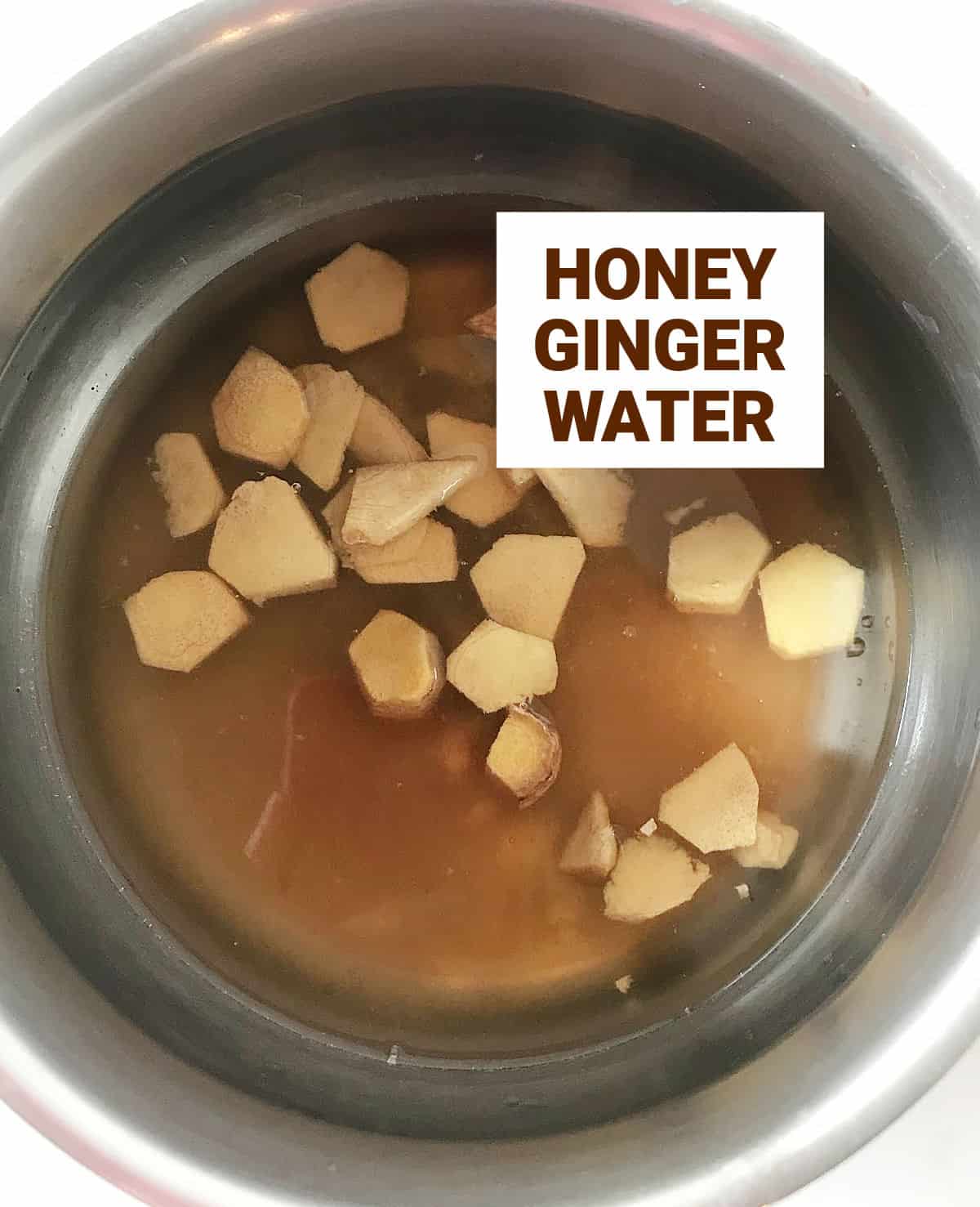 Top view of metal saucepan with ingredients for ginger honey syrup.