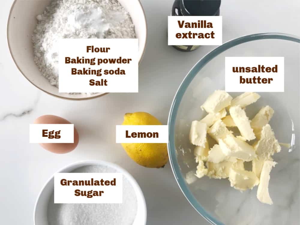 Lemon cookies ingredients.in bowls on white surface
