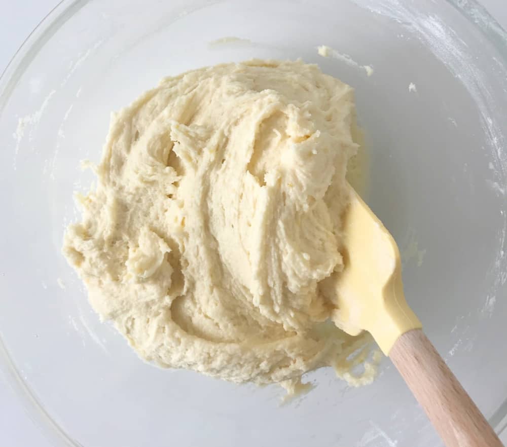 Lemon cookie batter in a glass bowl with a spatula.