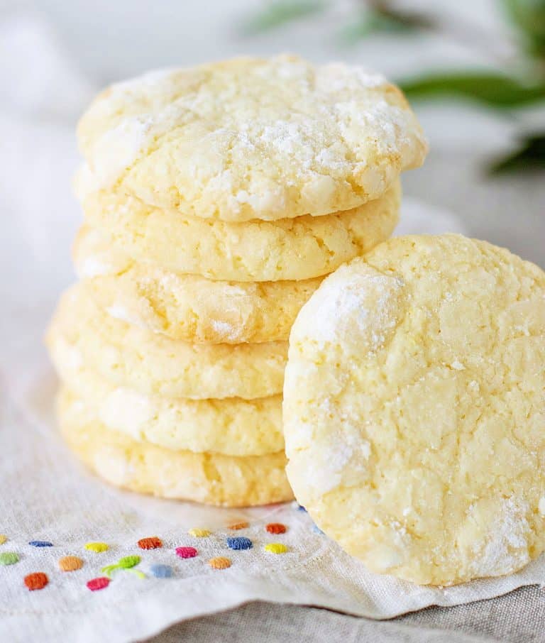 Several lemon crinkle cookies stacked on a white napkin with colored dots.
