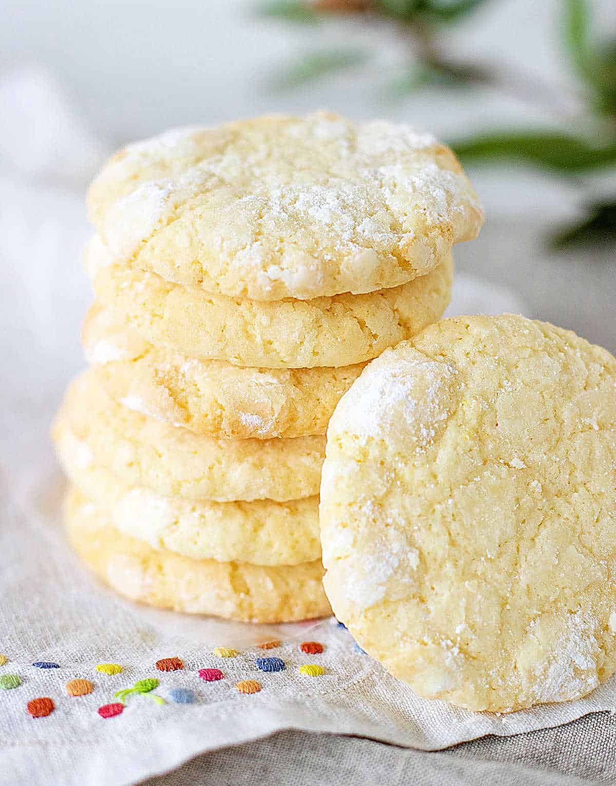 Stack of several lemon crinkle cookies on a color dotted white napkin.