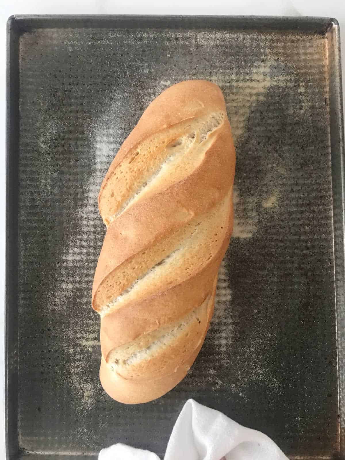 Baked loaf of bread on metal sheet.