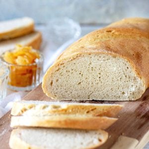 Close up semolina bread with slices on a wood board, grey background, lemon jam.