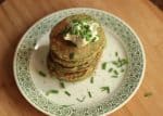 Green and white plate with stack of swiss chard pancakes, wooden surface