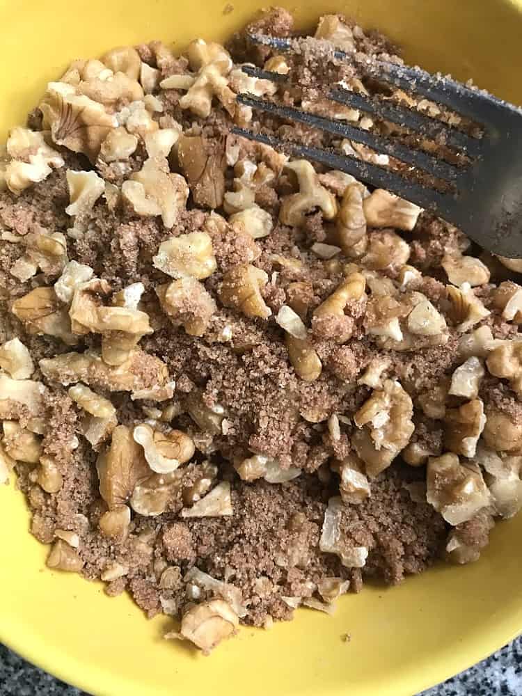 Yellow bowl with walnut crumble topping, fork