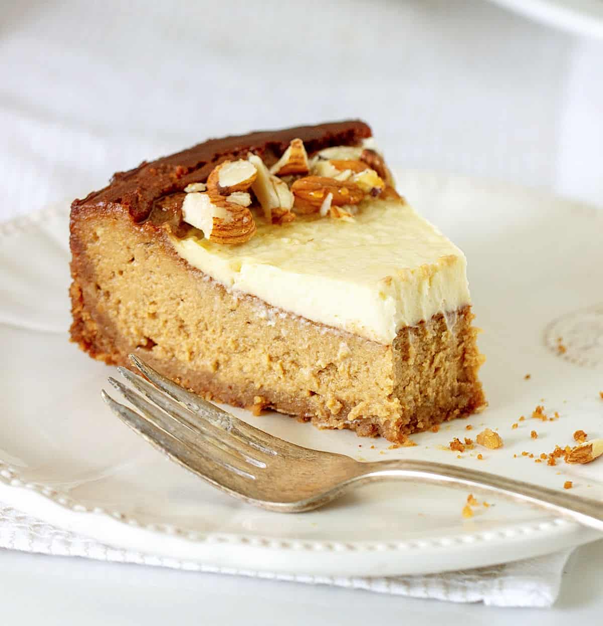 Close-up of partially eaten slice of brown sugar cheesecake on white plate with fork.