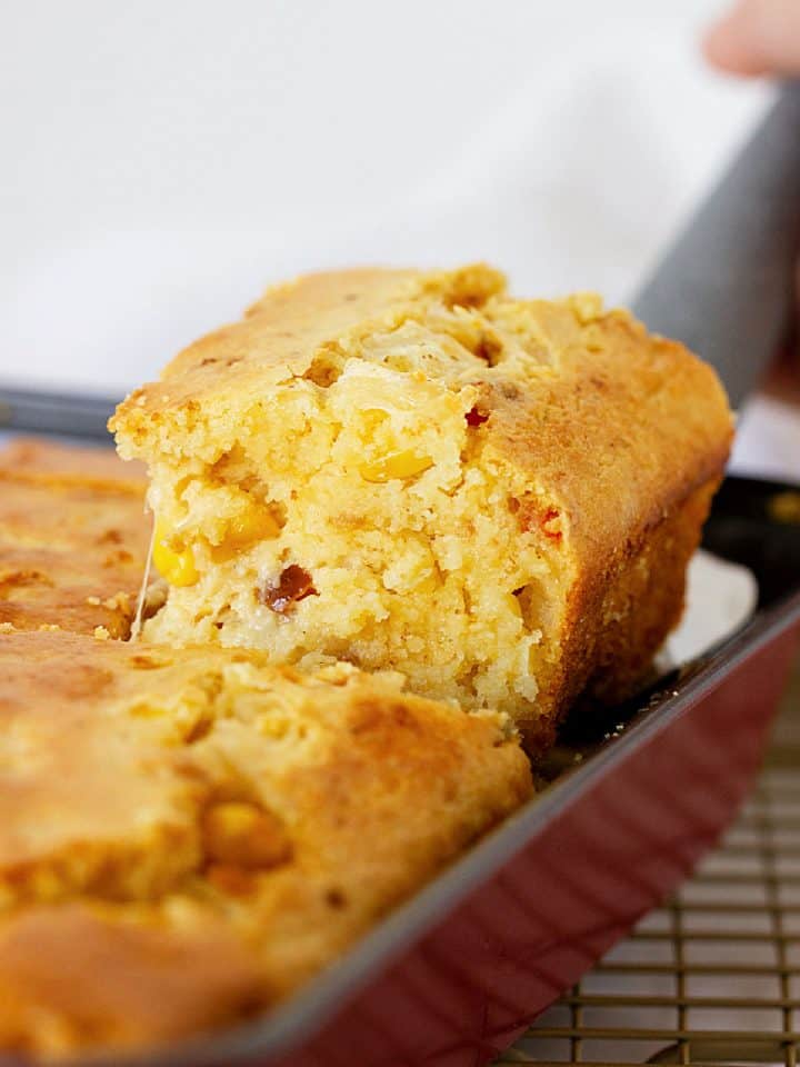 Lifting a square of cheese cornbread from pan