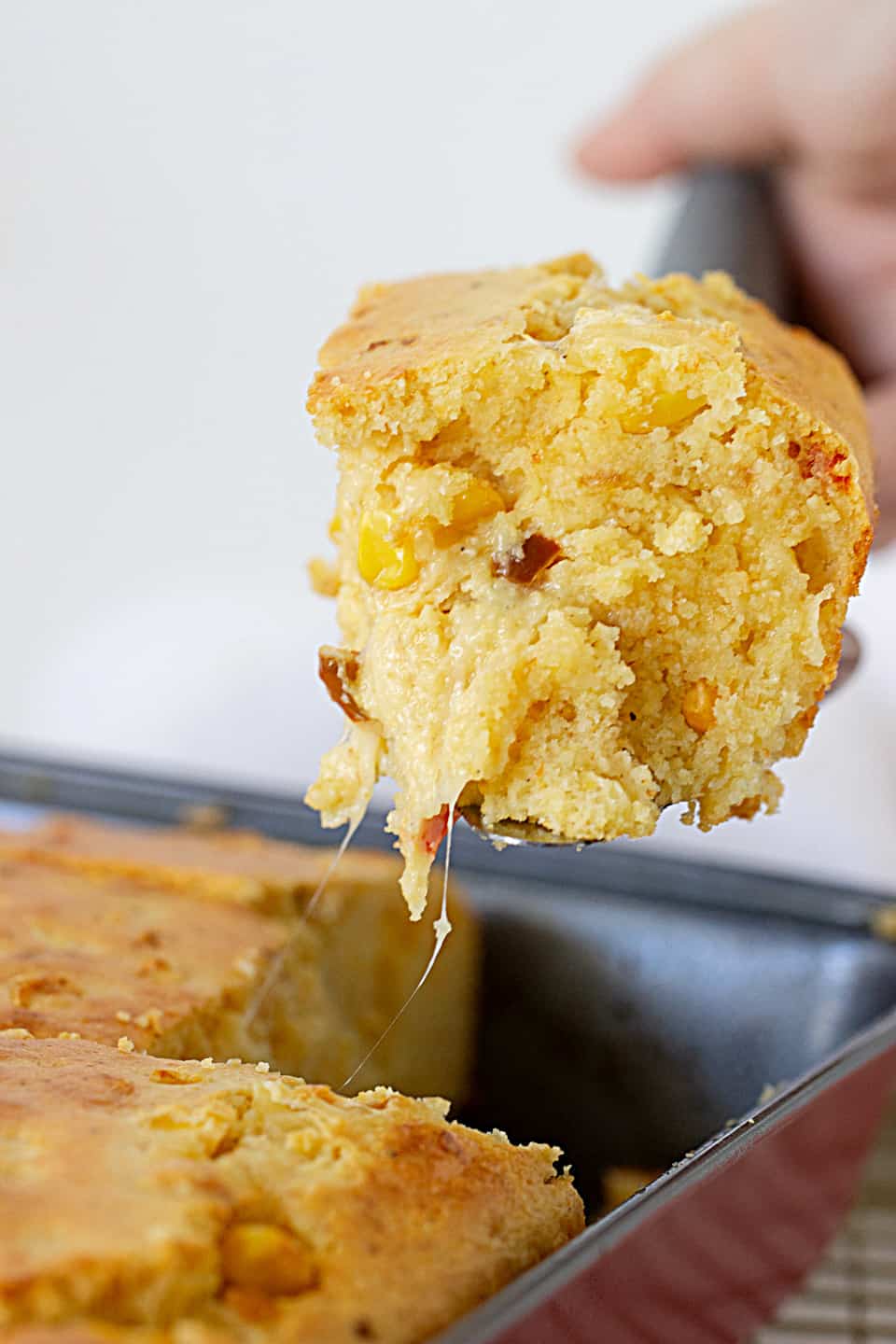 Taking a square of cheese cornbread from pan