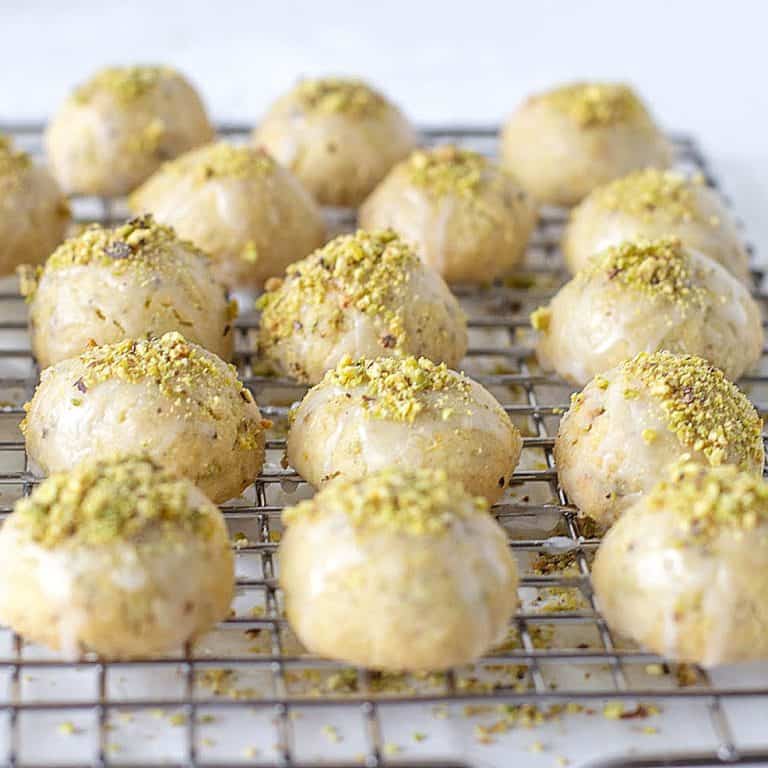 Rows of glazed pistachio cookies on a wire rack.