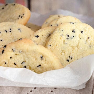 Several white and black sesame cookies enclosed by silk paper.