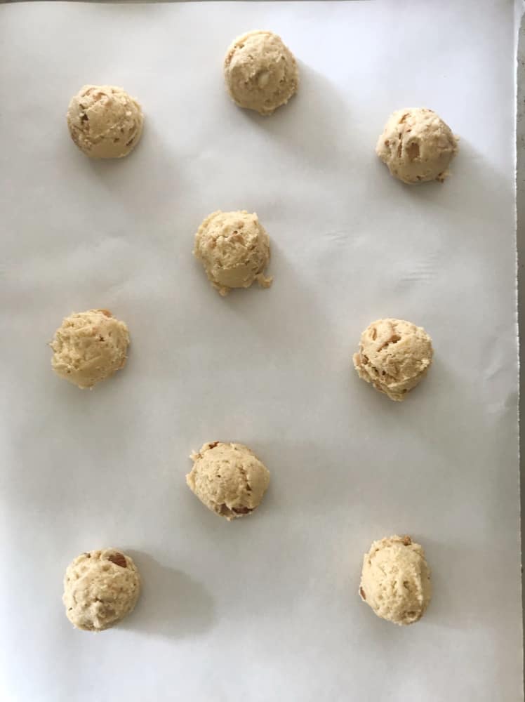 Raw balls of white chocolate cookies on parchment paper