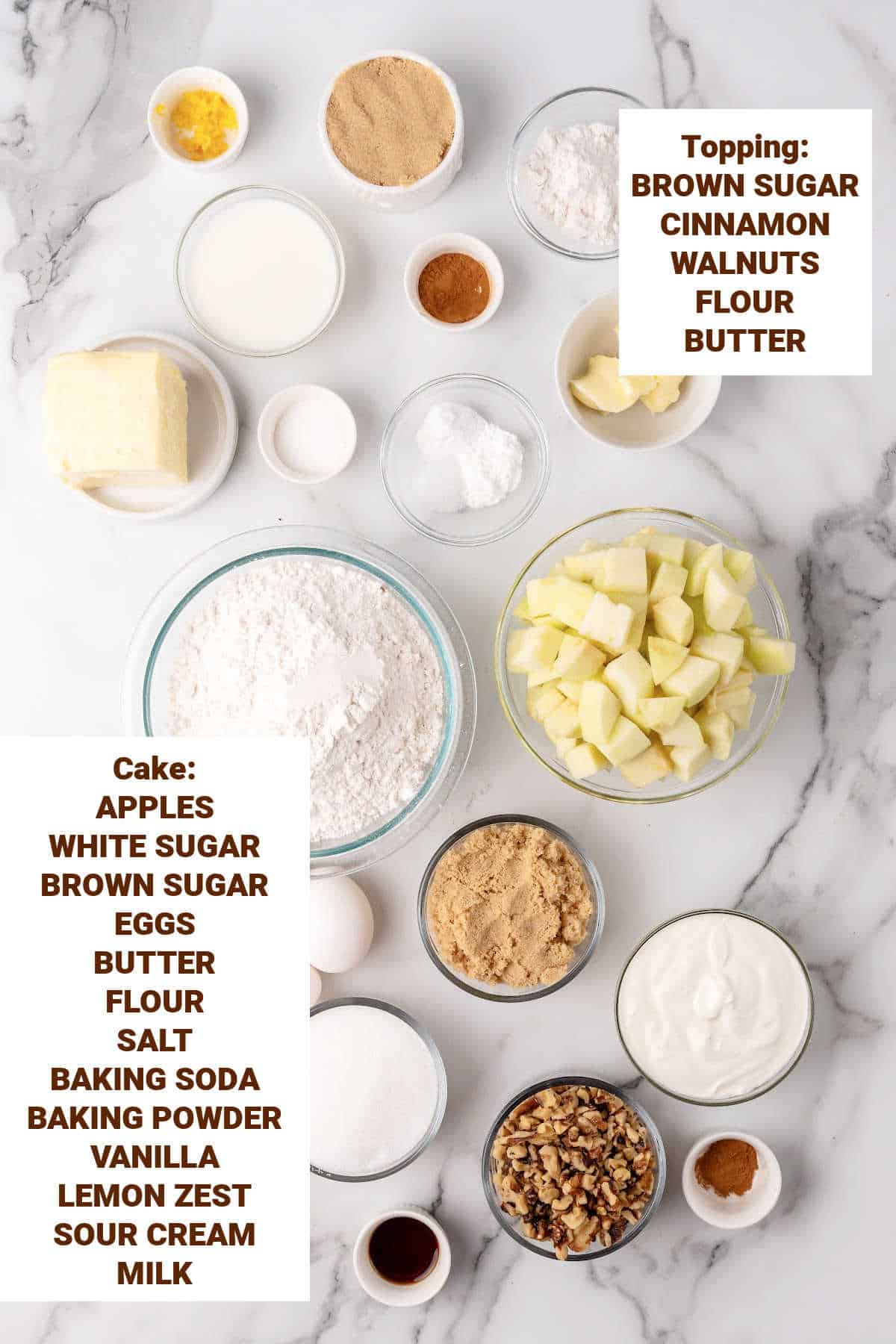 White marble surface with bowls containing ingredients for apple cinnamon walnut cake including butter, sour cream, milk, sugars, lemon, flour.