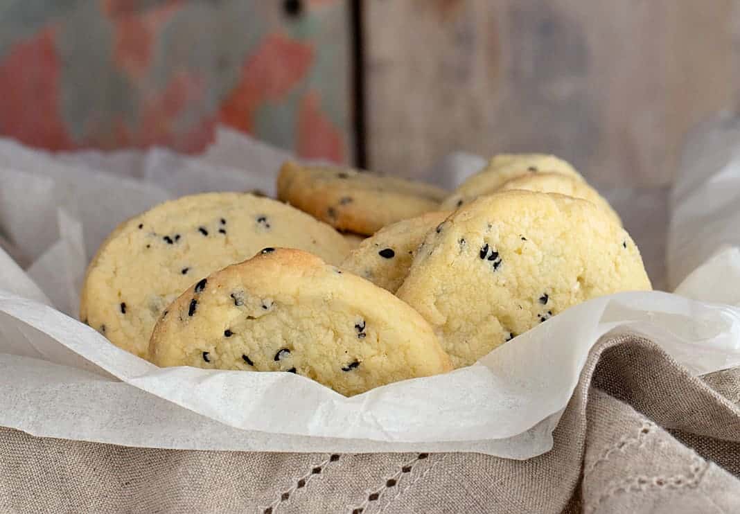 Cookies with black sesame over napkin and silk paper; wooden background.