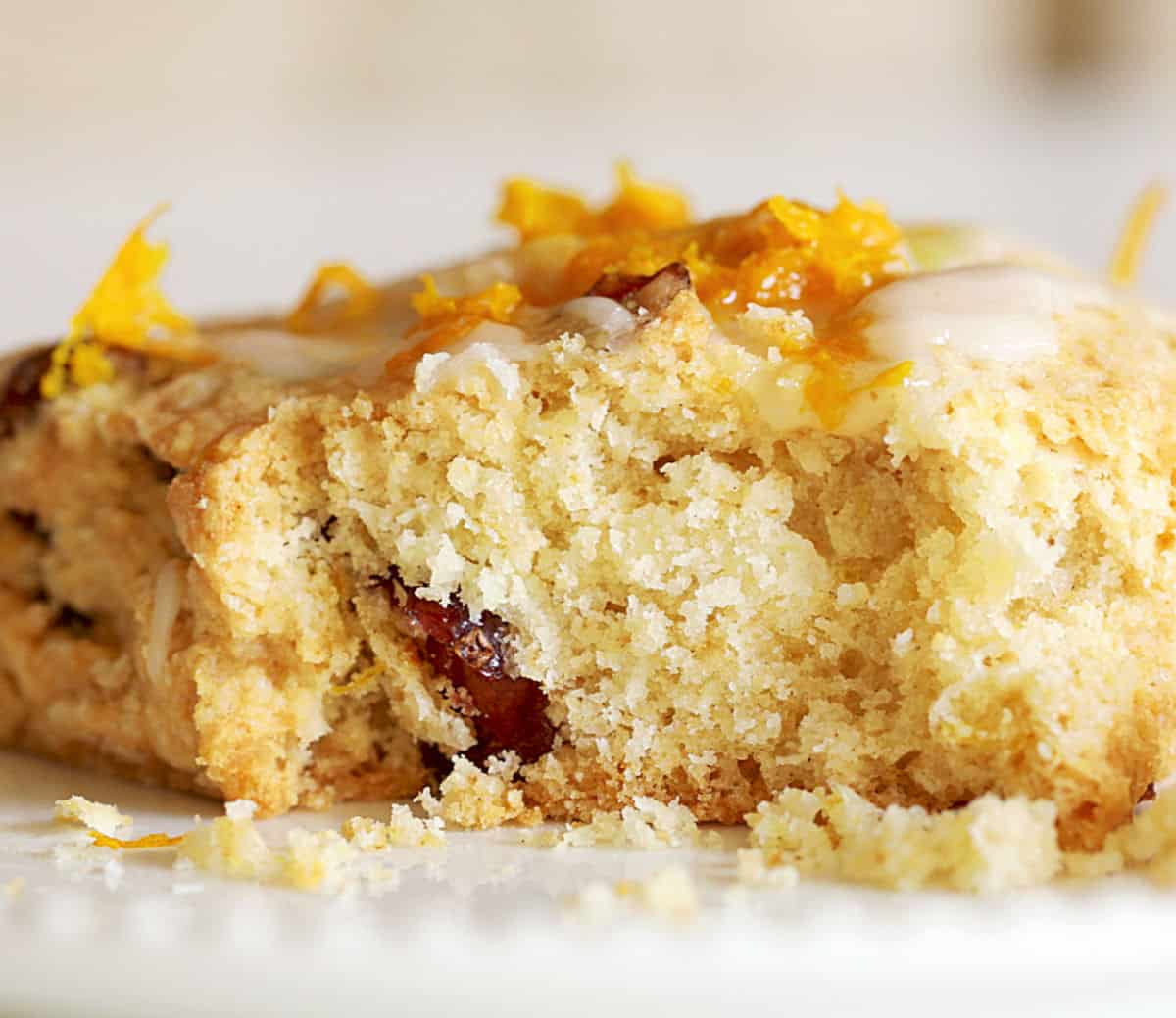 Close-up image of bitten cranberry orange scone on whitish background.