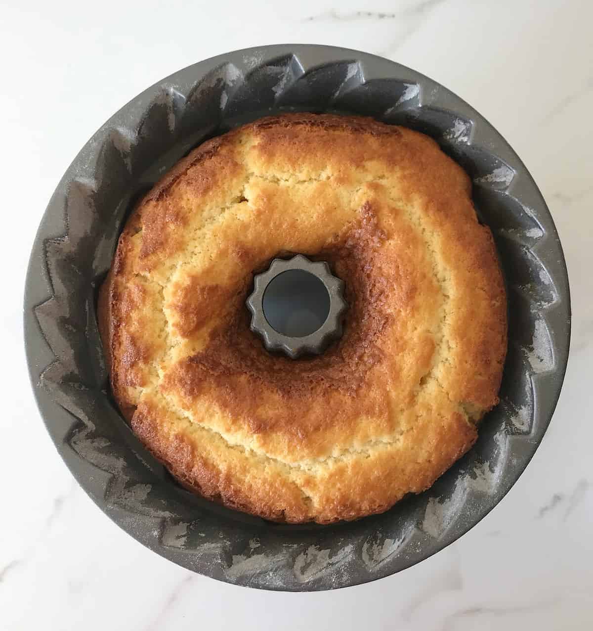 Aerial view of bundt pan with baked cake on white marble surface