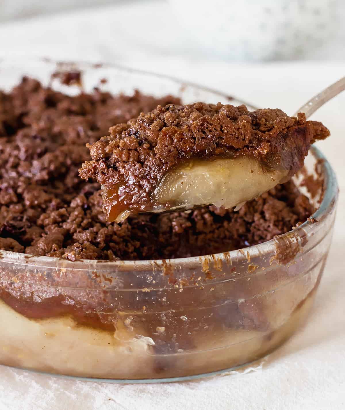 Serving chocolate apple crisp with a spoon from the glass dish